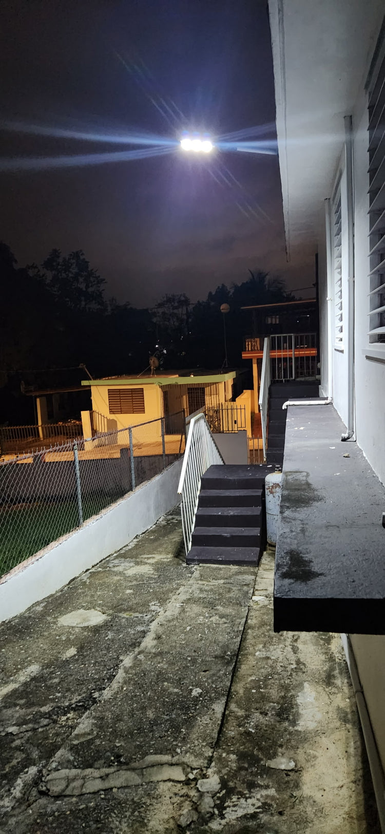 Lámpara solar LED instalada alumbrando la terraza y las escaleras de una casa de noche