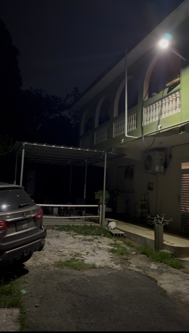 Lámpara solar LED instalada alumbrando la entrada de una casa de noche
